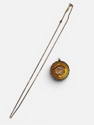 a gold plated necklace with a chain and a small badge on it