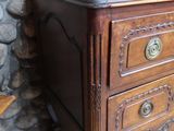une commode en bois à deux tiroirs, sur laquelle est posé un vase
