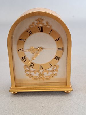 a small gold clock with roman numerals on it