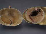 pair of antique brass hats on a gray background