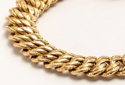 une photo d'un bracelet à maillons dorés posé sur une surface blanche