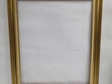 gold picture frame on a white background with a vase of flowers in the foreground
