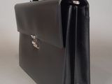 black leather briefcase sitting on a white surface with a silver clasp