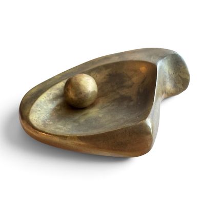 un objet métallique contenant une boule, posé sur une surface blanche