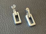 pair of silver earrings on a black leather surface