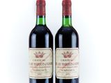two bottles of red wine sitting next to each other on a white surface
