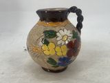 a small vase with flowers painted on it on a white surface