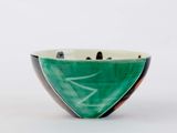 a green and black bowl sitting on a white surface