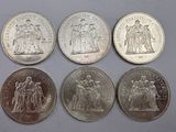 six different coins are shown on a table with a white background