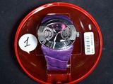 une montre violette posée sur une assiette rouge