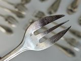 a person holding a fork in front of a tray of silverware