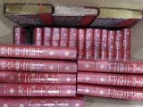 de nombreux livres rouges empilés dans une boîte posée par terre