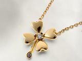 un gros plan sur un collier en or orné d'un pendentif en forme de trèfle à quatre feuilles