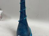 une bouteille en verre bleue sur laquelle est collée une étiquette