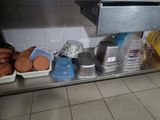 several trays of food sit on a stainless steel shelf in a kitchen