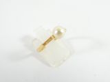a close up of a ring with a pearl in it on a white surface