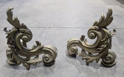 pair of antique brass scroll and leaf bookends on a concrete floor