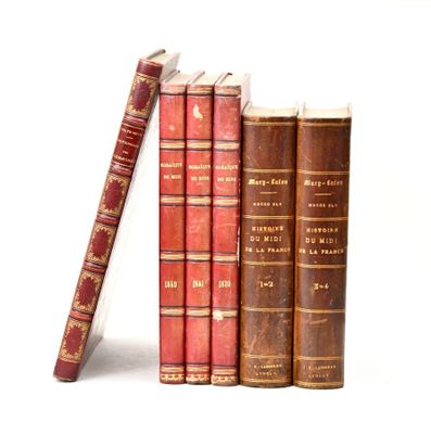 several old books are stacked on top of each other on a white surface