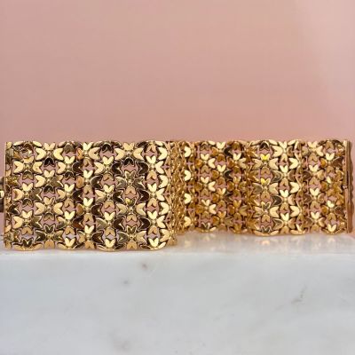 a close up of a gold bracelet on a marble surface