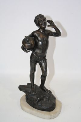 statue en bronze représentant un garçon tenant un ballon de football sur un rocher