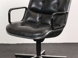 an image of a black leather office chair with wheels on a carpeted floor