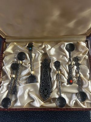 trois cuillères en argent dans une boîte recouverte d'un tissu doré