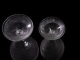 two clear glass bowls sitting next to each other on a black surface