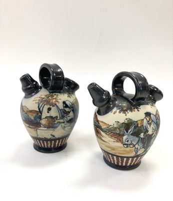 pair of ceramic vases with figures on them on a white background