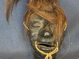 a black mask with a brown hair and a tag on it