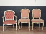 Dans une pièce, trois chaises sont alignées contre un mur noir