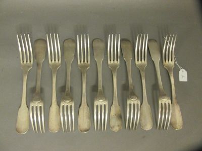 six fourchettes et six cuillères sont disposées en rangée sur une table
