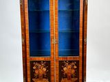 une vieille armoire en bois avec des portes vitrées, posée sur un parquet
