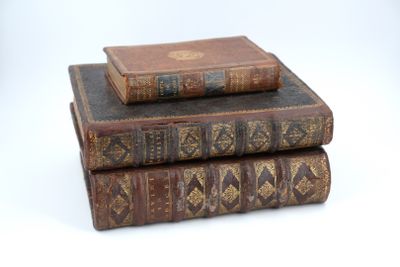 trois vieux livres empilés sur une surface blanche