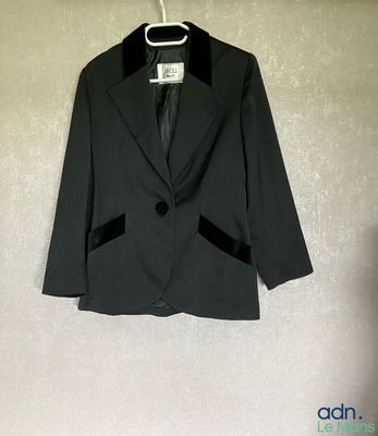 une veste noire accrochée au mur à côté d'un cintre