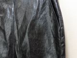 black leather skirt hanging on a hanger against a white wall