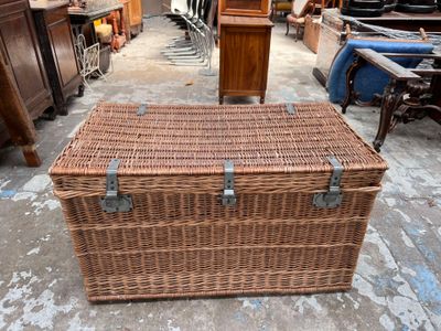 a wicker trunk sitting on the floor in a warehouse