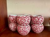 trois vases rouges et blancs posés sur une étagère en bois, à côté d'un bol