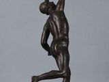 a bronze statue of a man holding a tennis racquet on a wooden base