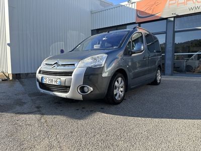 La camionnette argentée est garée devant un immeuble, sur un parking.