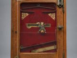 une vieille horloge en bois avec un couvercle rouge et une clé sur le devant