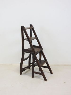 an old wooden step stool sitting in a room next to a white wall