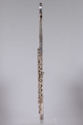 a silver flute on a clear stand against a gray background