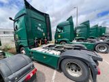 many green semi trucks parked in a parking lot