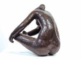 statue of a man sitting on his knees with his back to the camera