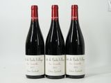 trois bouteilles de vin rouge sont alignées sur une surface blanche