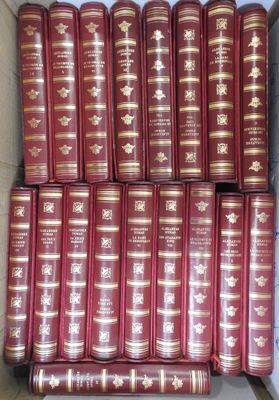 many red books are stacked in a cardboard box on a table
