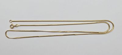 a close up of a gold chain on a white surface