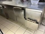 plan de travail en acier inoxydable dans une cuisine professionnelle, avec tout un tas de bouteilles