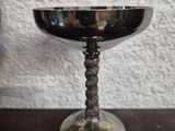 a small silver bowl on a table next to a bottle