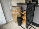 une ardoise posée sur un support à côté d'un tonneau de vin